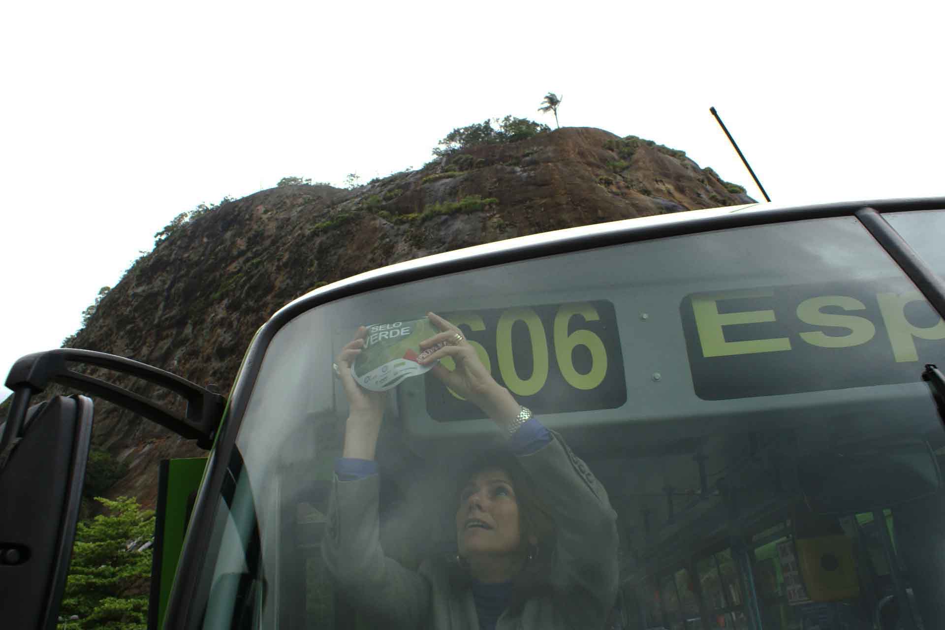 Secretaria do Meio Ambiente, Marilene Ramos, cola o adesivo do Selo Verde em um ônibus durante o lançamento da campanha, na Lagoa (RJ). Divulgação Fetranspor